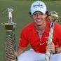 Golfer Rory McIlroy poses with trophies he won at the PGA season-ending tournament in Dubai in 2012.