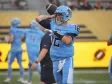 A football player in a light blue uniform with the number 12 prepares to throw the ball during a game.