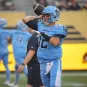 A football player in a light blue uniform with the number 12 prepares to throw the ball during a game.
